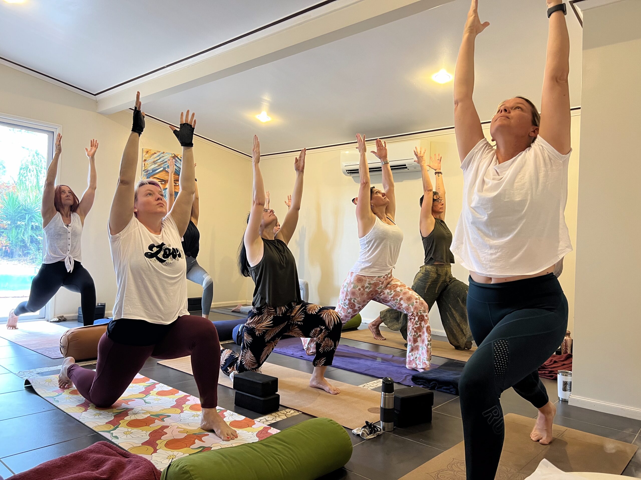 Women in a 200-hour yoga teacher training practicing strong standing poses in Mackay,Embodied yoga teacher training class led in Mackay, Australia,Group yoga practice during 200-hour yoga teacher training in Queensland