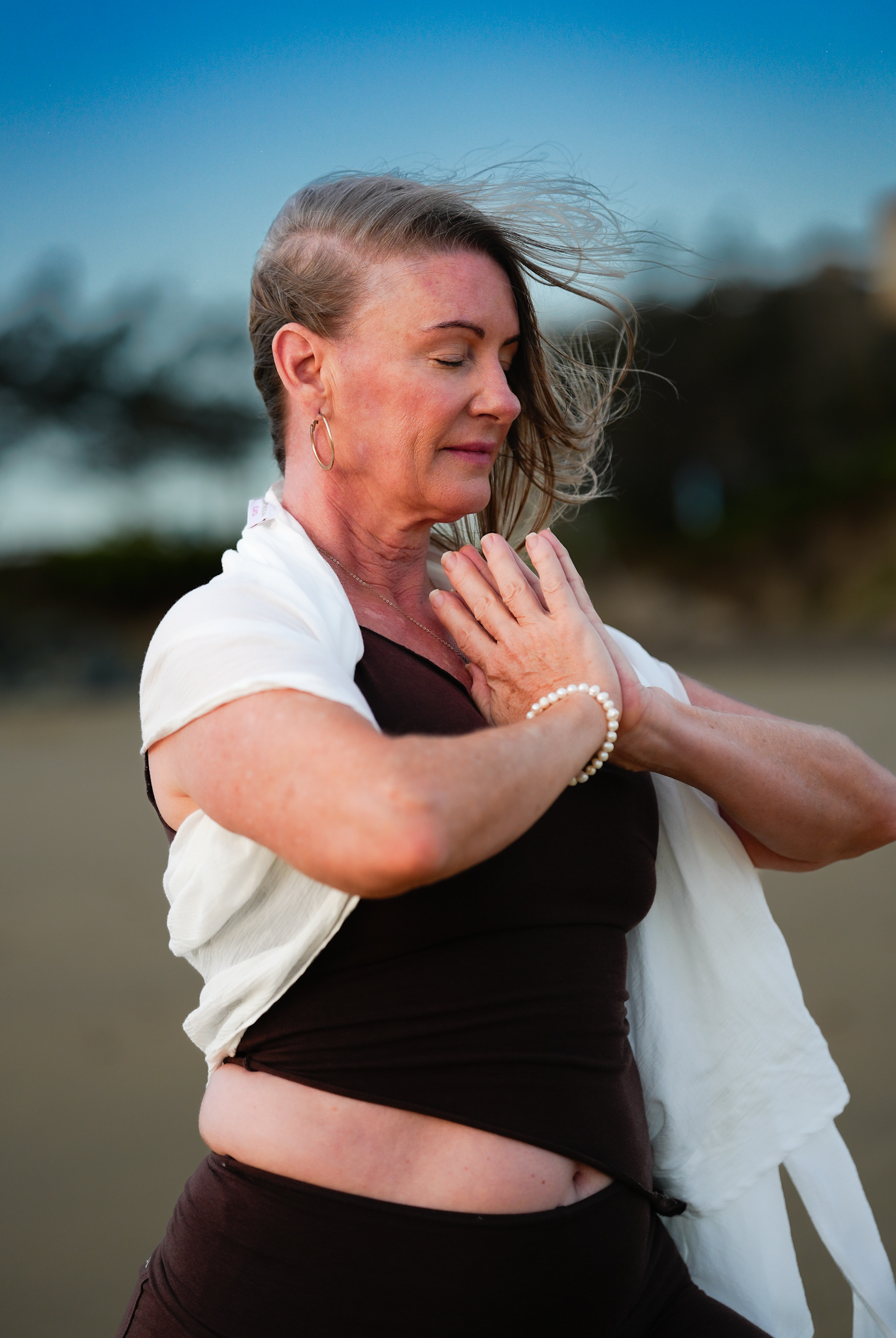 Woman practising a grounded yoga posture on the beach in Mackay, Queensland, demonstrating strength, balance, and embodied movement in a natural coastal setting.